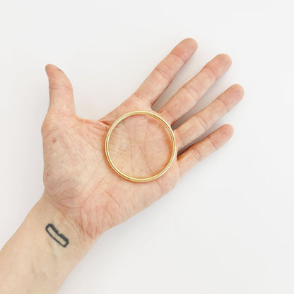 Golden metal ring held in hand, 50mm
