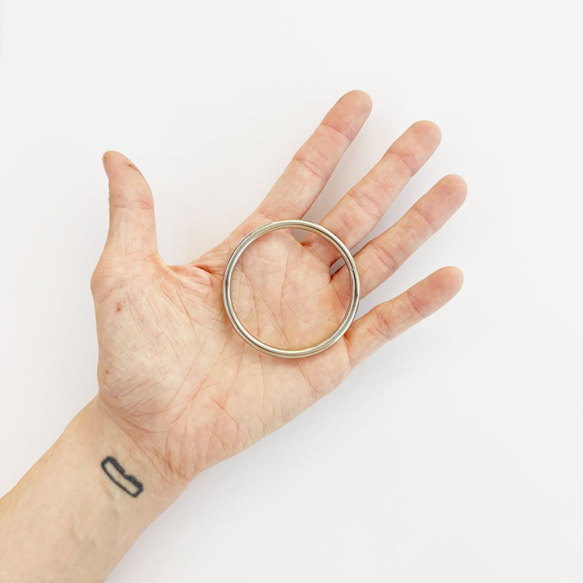 Silver metal ring held in hand, 50mm