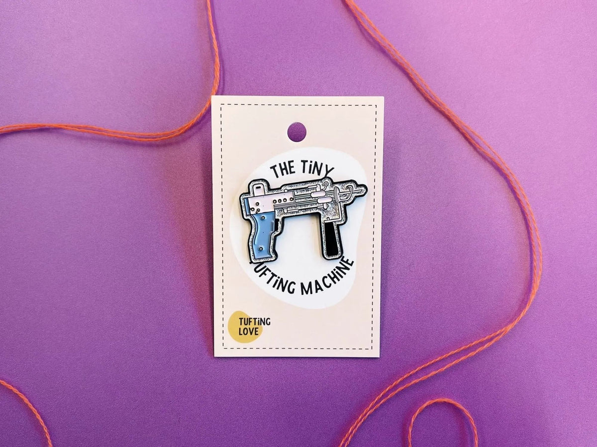 Enamel pin shaped like a tiny tufting machine